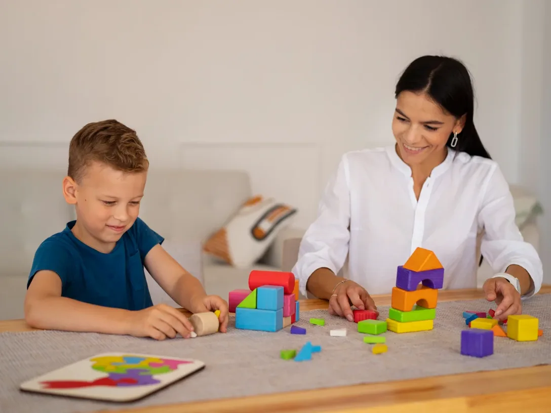 Young child playing with building blocks alongside an adult
