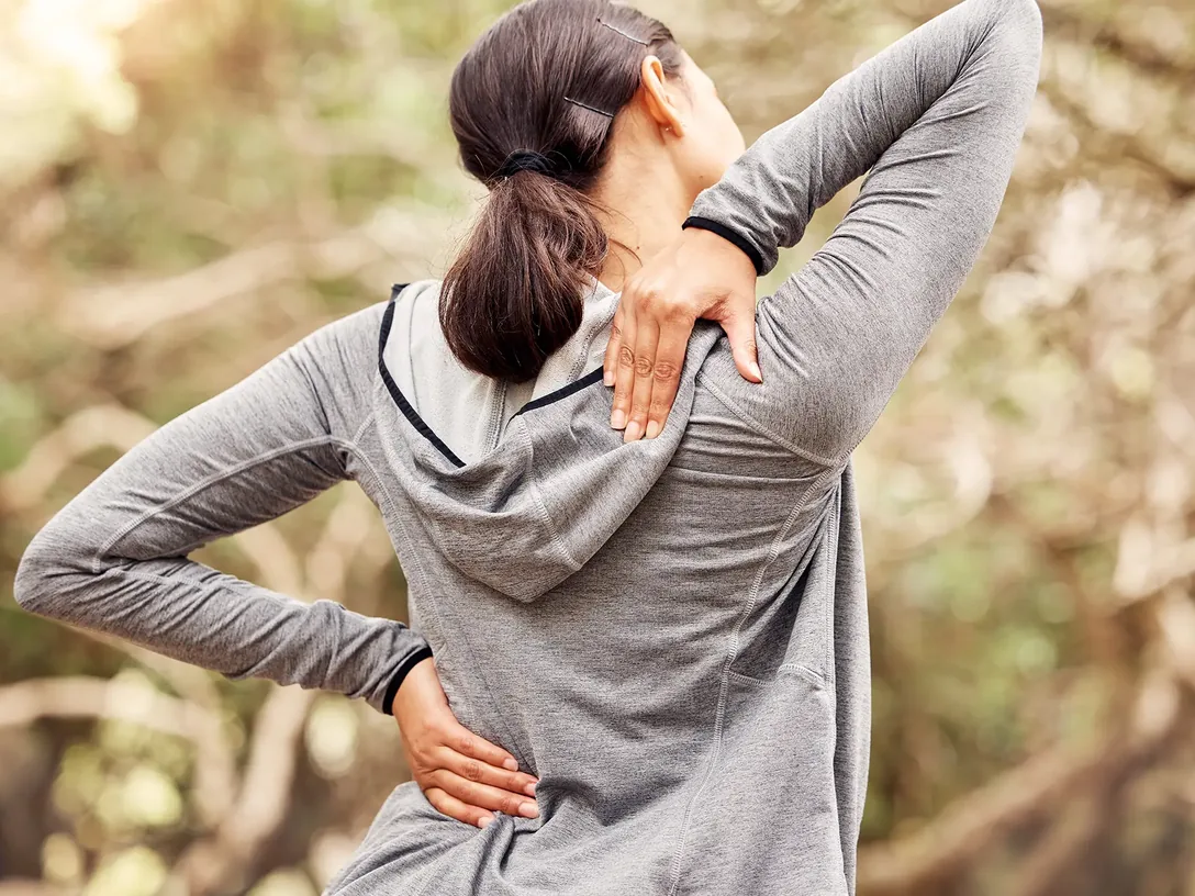 Woman holding her lower back outdoors