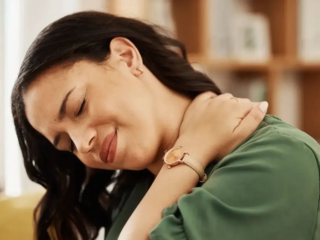 Woman holding her neck and shoulder in discomfort