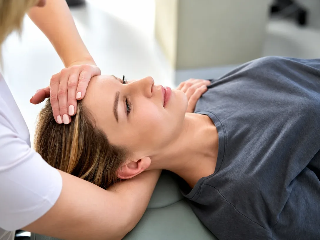 Clinician treating a patient's head and neck on a treatment table