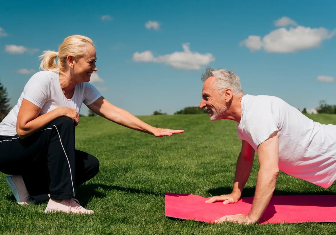 Two people doing guided floor exercises on mats outdoors