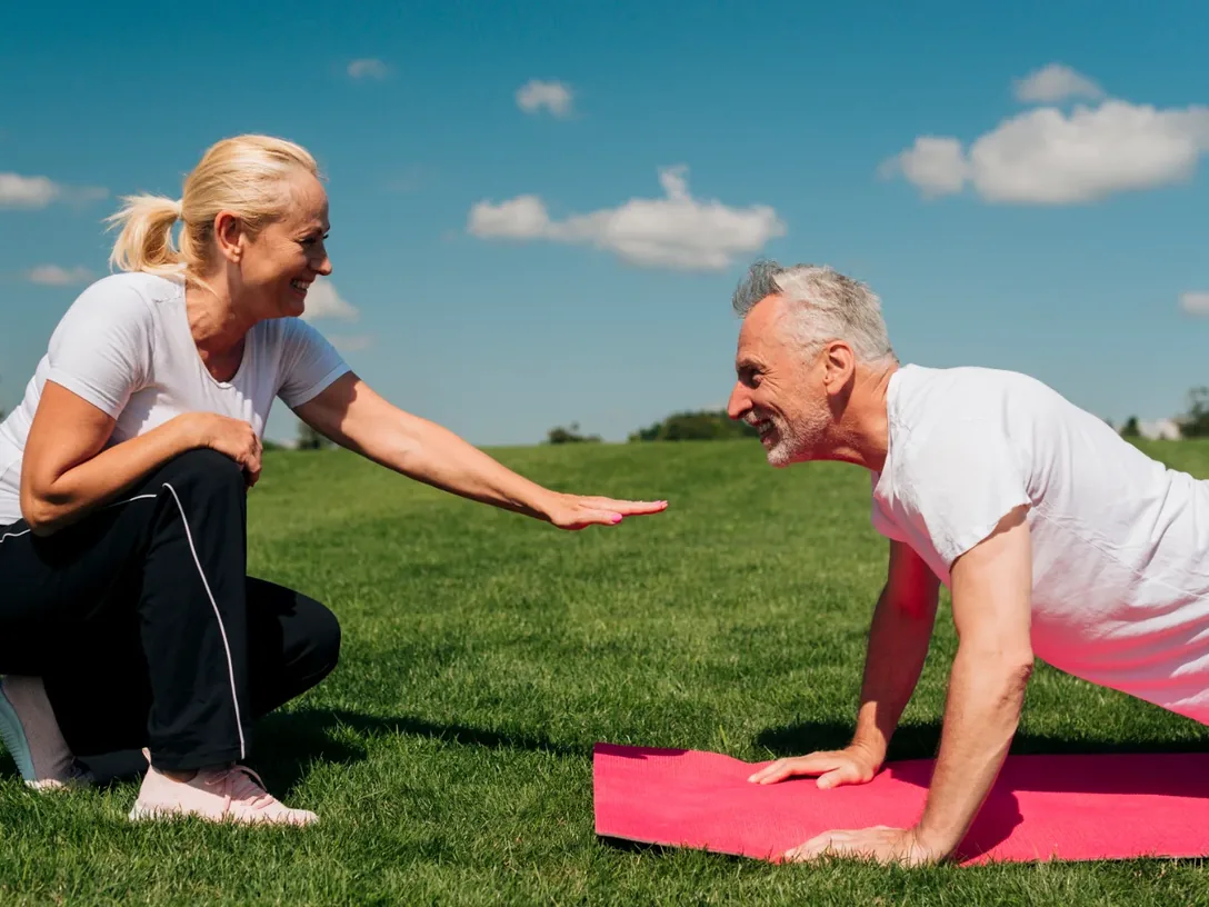 Two people doing guided floor exercises on mats outdoors
