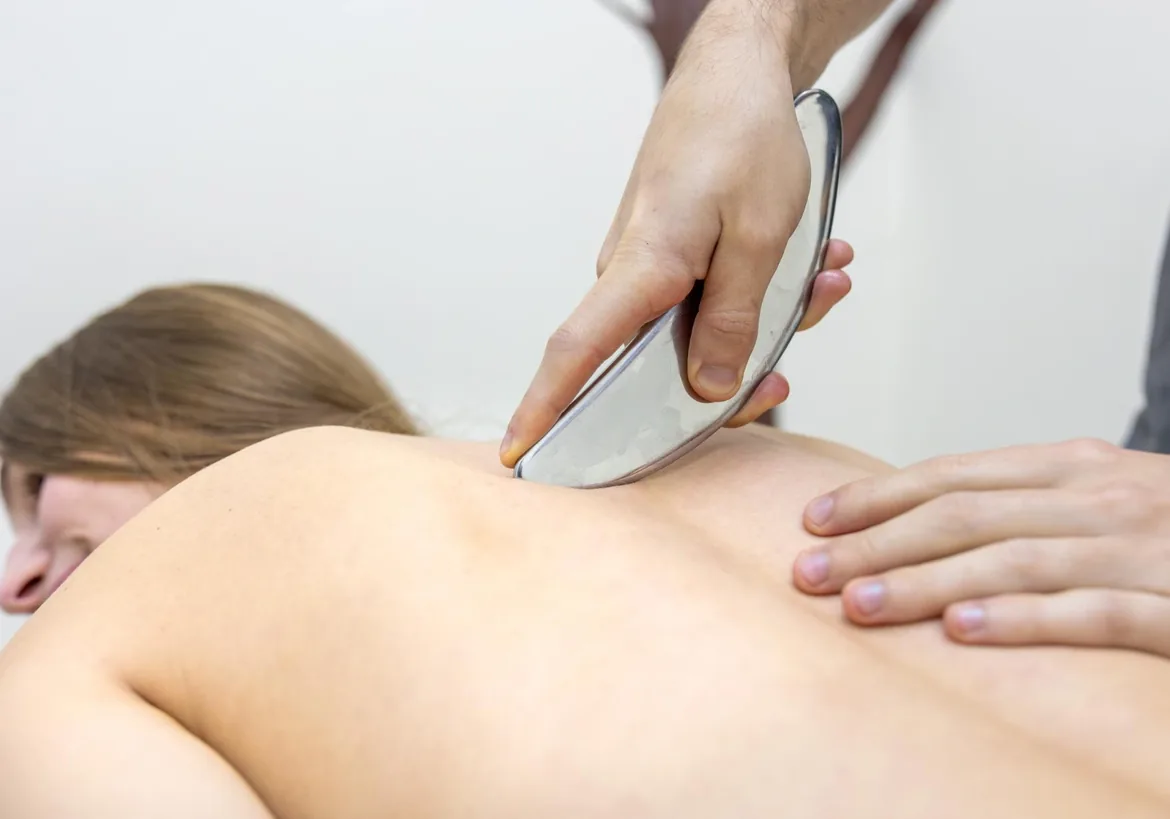 Clinician using a stainless steel instrument on a patient's back