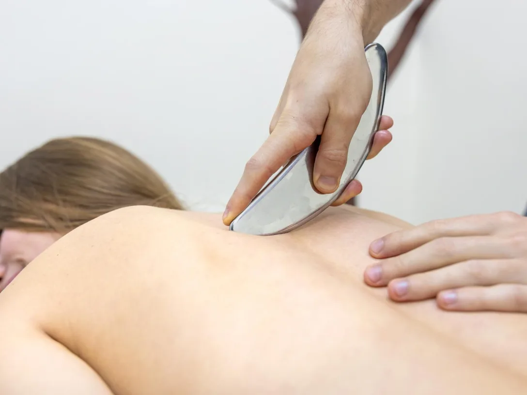 Clinician using a stainless steel instrument on a patient's back