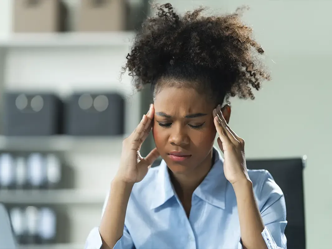 Woman at a desk holding her head
