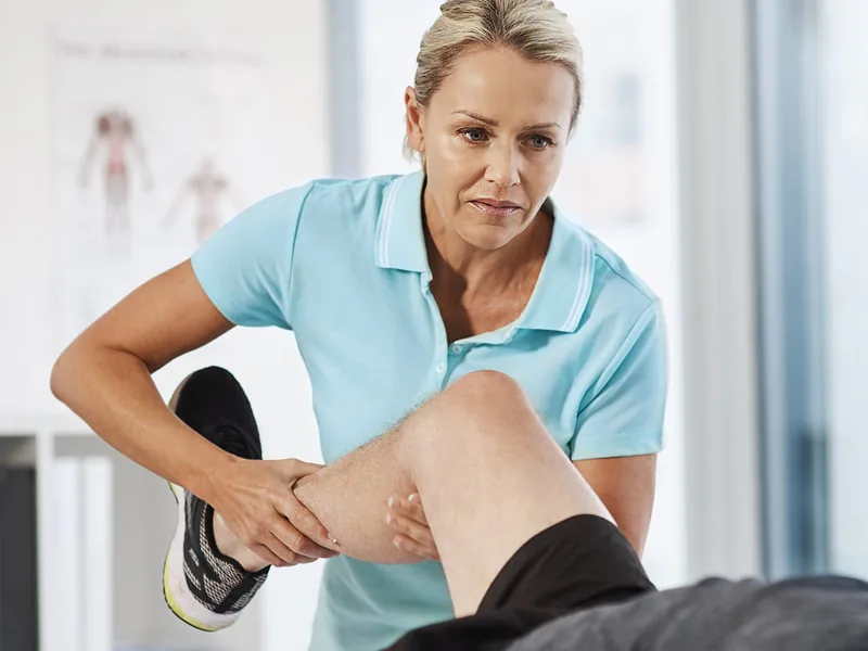 Clinician moving a patient's leg on a treatment table