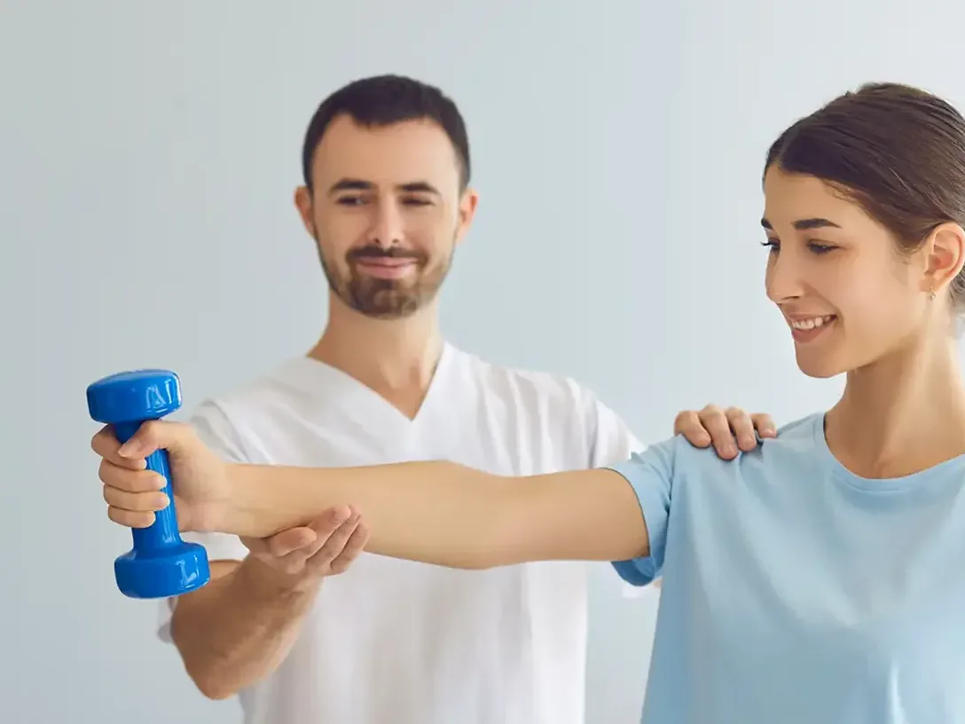 Clinician guiding a patient's arm through a dumbbell exercise