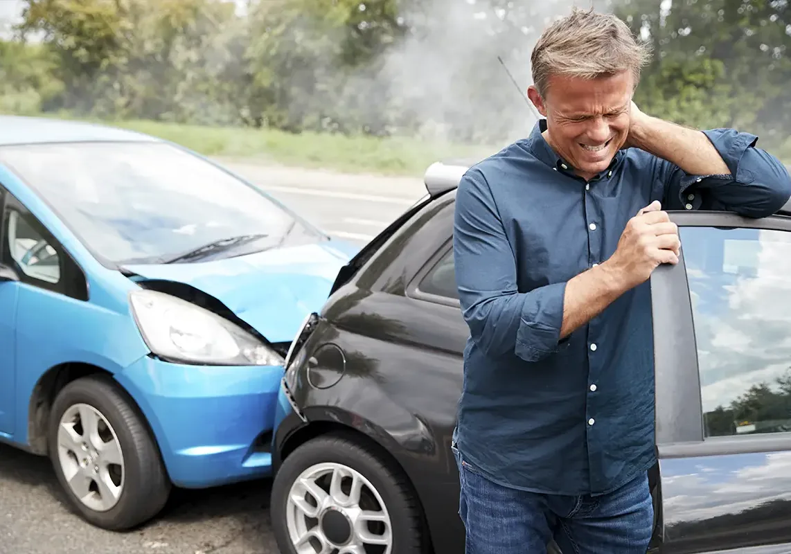 Man holding his neck beside two damaged cars