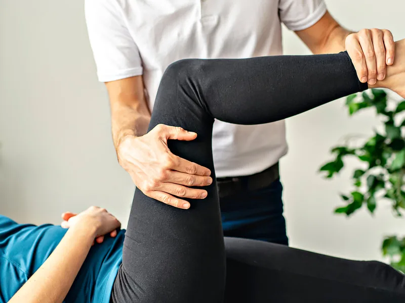 Clinician stretching a patient's leg on a treatment table