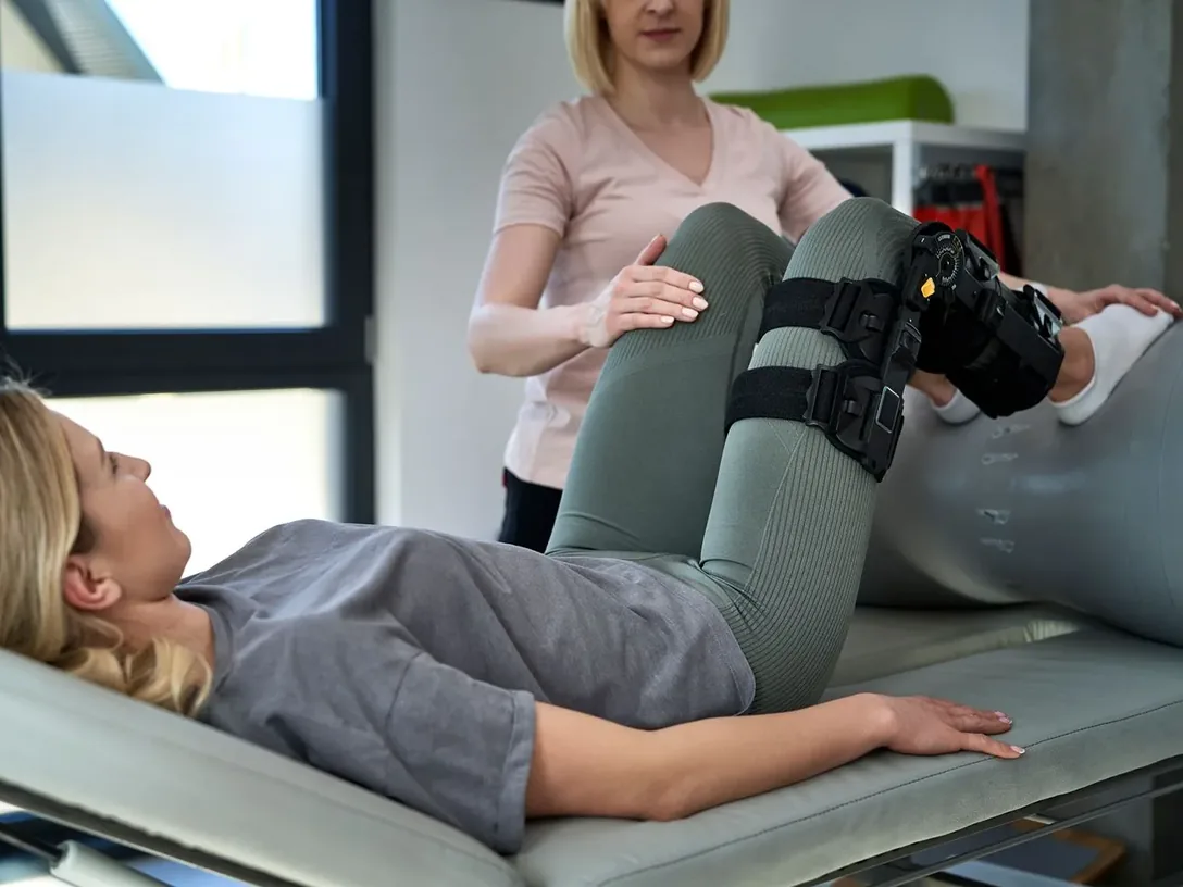 Clinician stretching the leg of a patient wearing a knee brace