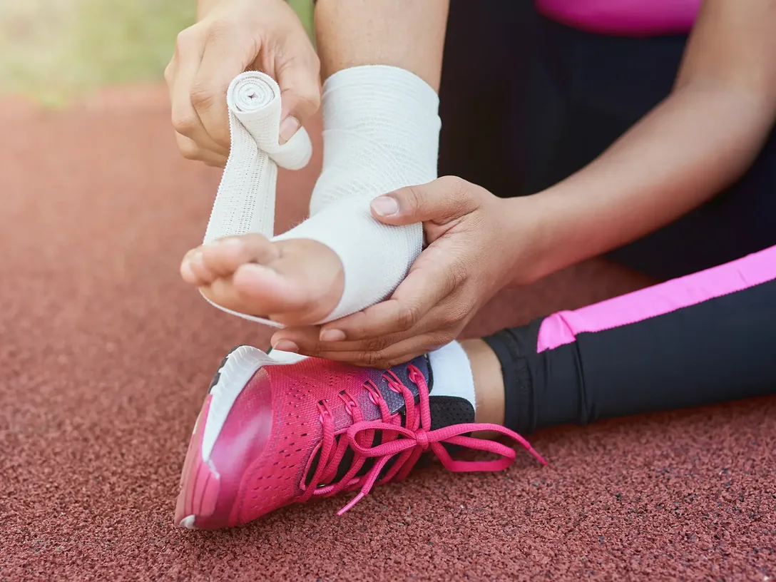 Ankle being wrapped with athletic tape on a running track