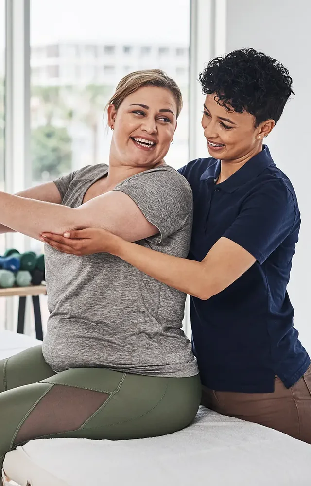 Clinician guiding a smiling patient through a weighted ball exercise