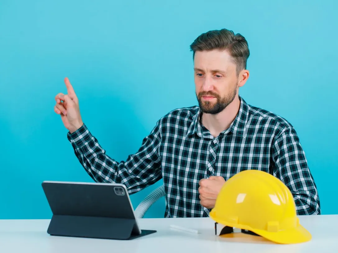 Man with a hard hat and a tablet at a desk